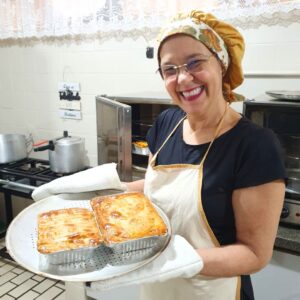 Gisele mostrando suas tortas que acabaram de sair do forno. Ela está sorridente